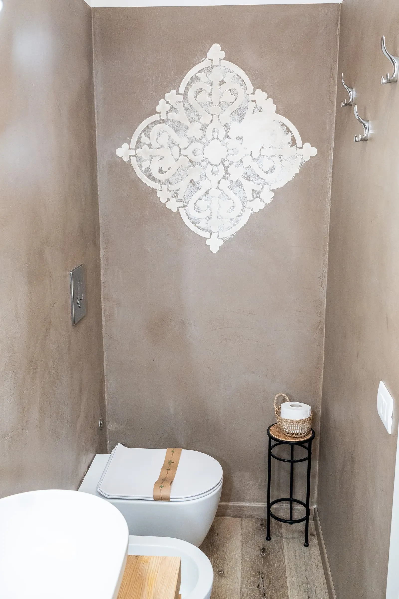 Bagno della camera Ciliegio con decoro in stucco bianco su parete color tortora