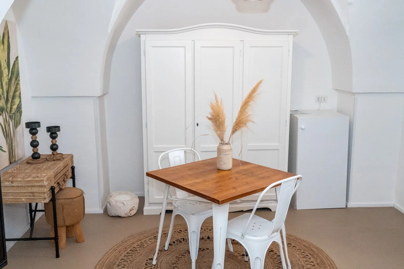 Zona giorno della Suite Fico con tavolo in legno sotto l'arco e armadio bianco