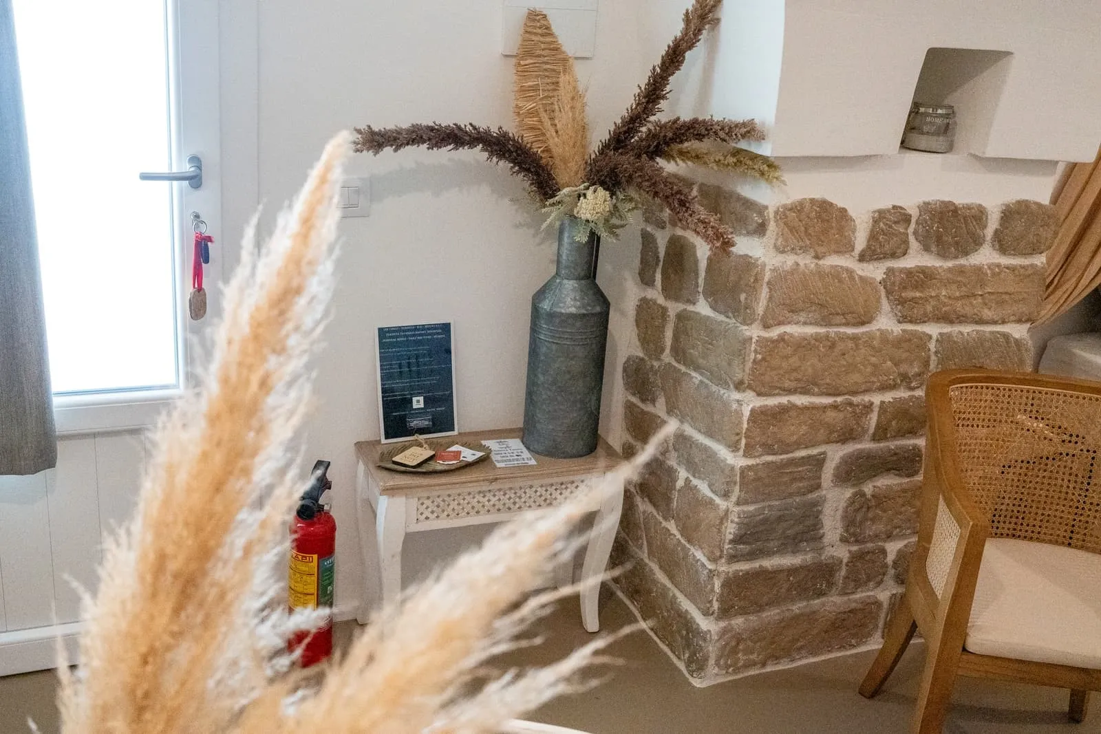 Angolo della Suite Fico con muro in pietra a vista, pampas e poltrona in rattan