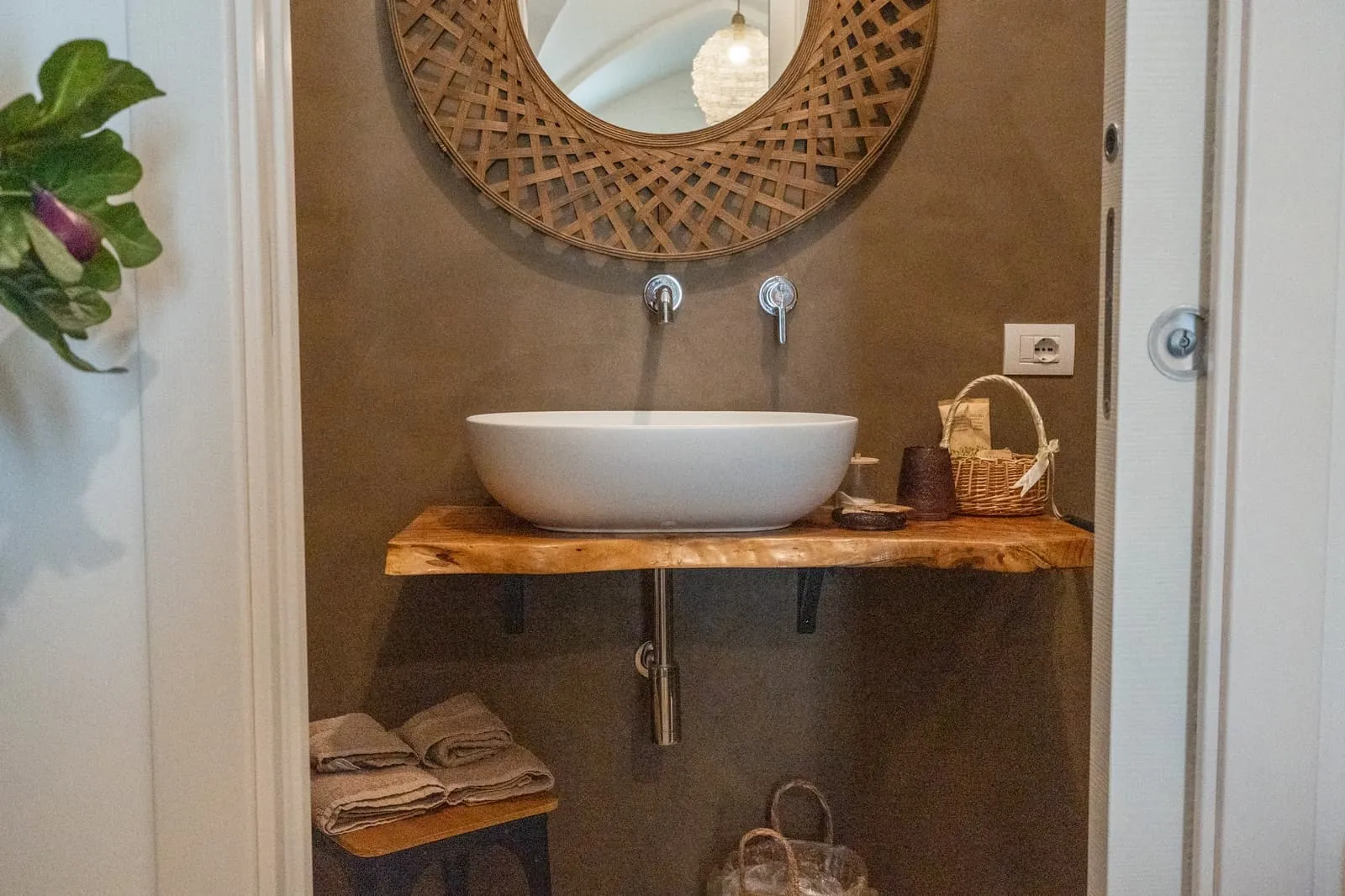Lavabo su mensola in legno massello e specchio in vimini, bagno della Suite Fico