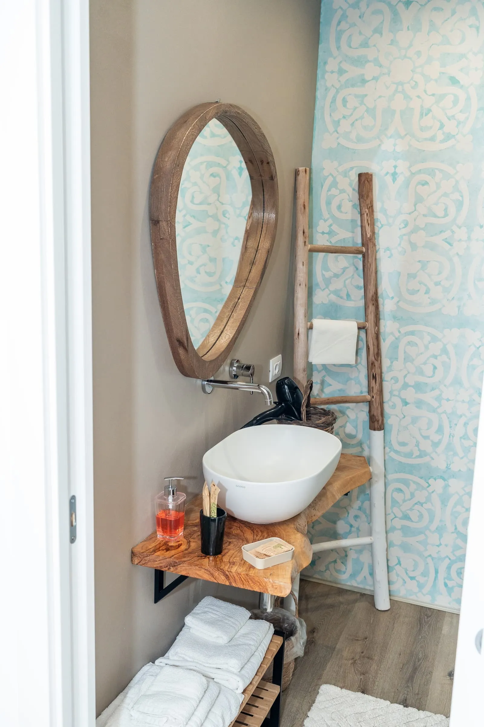 Bagno Mandarino con specchio ovale in legno, scala decorativa e piastrelle azzurre