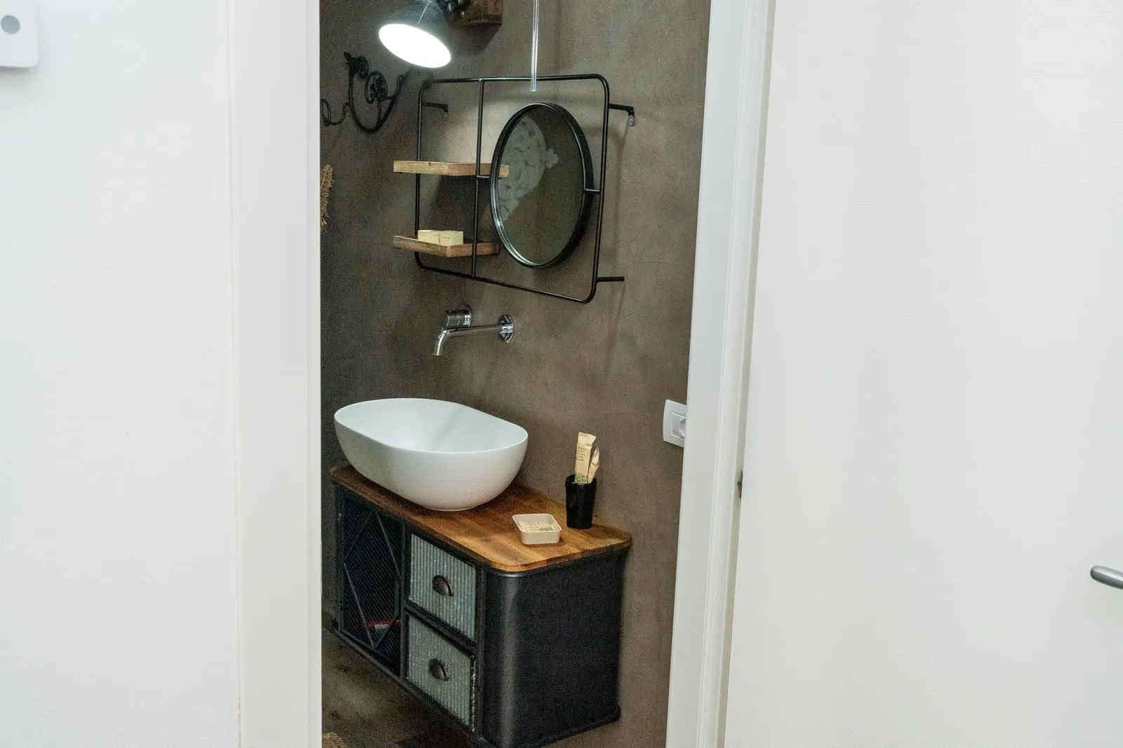 Lavabo d'appoggio su mobile nero e specchio rotondo, bagno Melograno